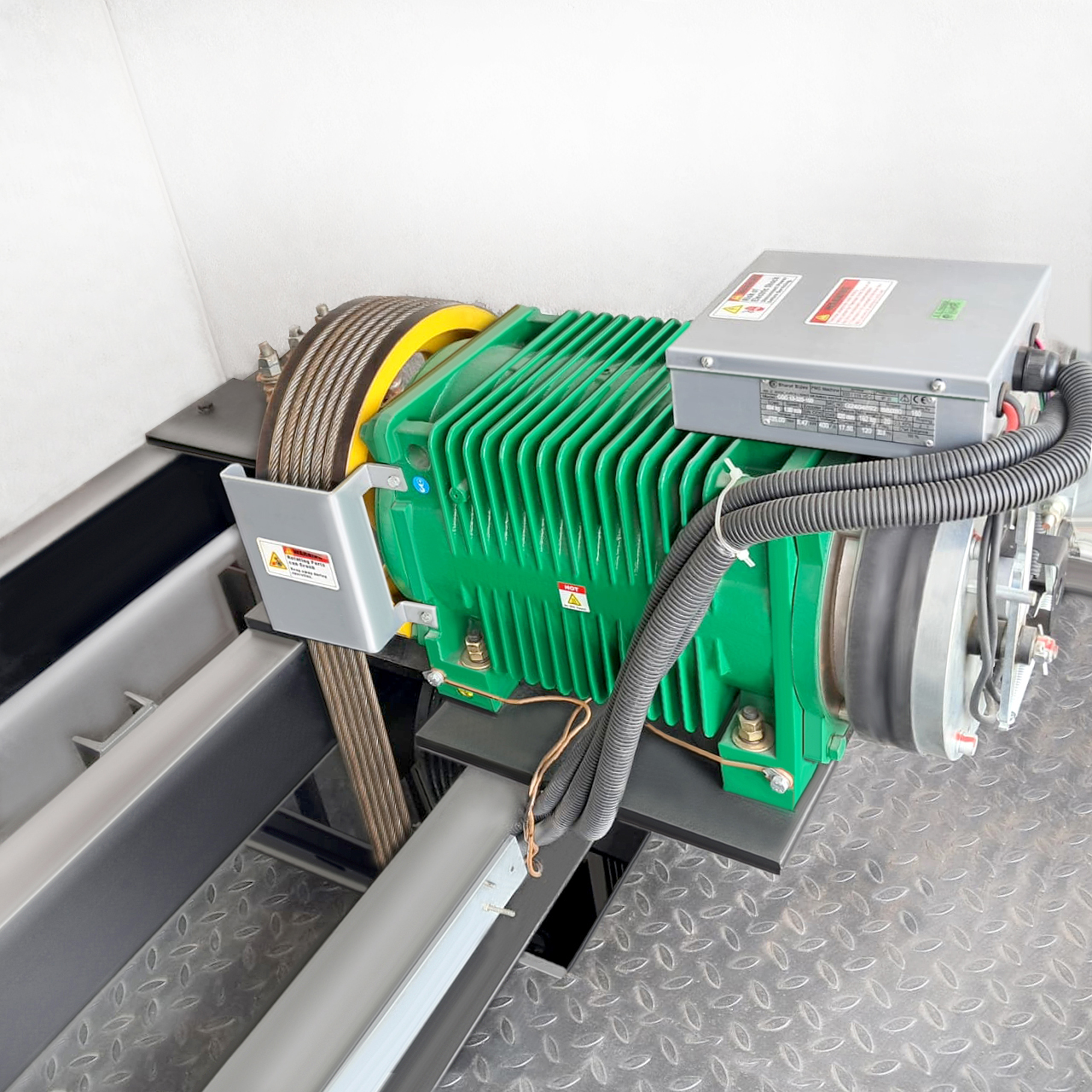 Industrial elevator machinery with green motor housing and cable system